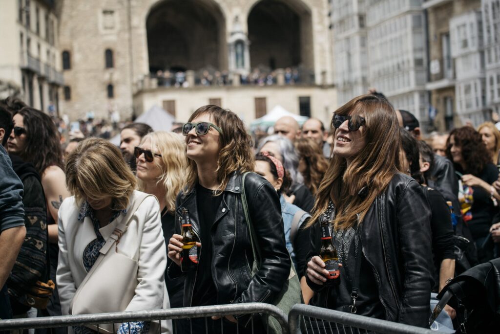Grupo de asistentes con chaquetas de cuero y cervezas en mano disfrutando de un concierto en el Azkena Rock Festival.