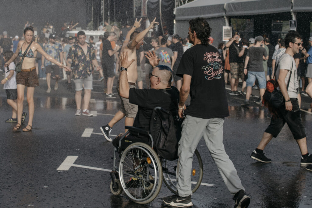 Asistente en silla de ruedas celebrando bajo un chorro de agua en el Azkena Rock Festival.