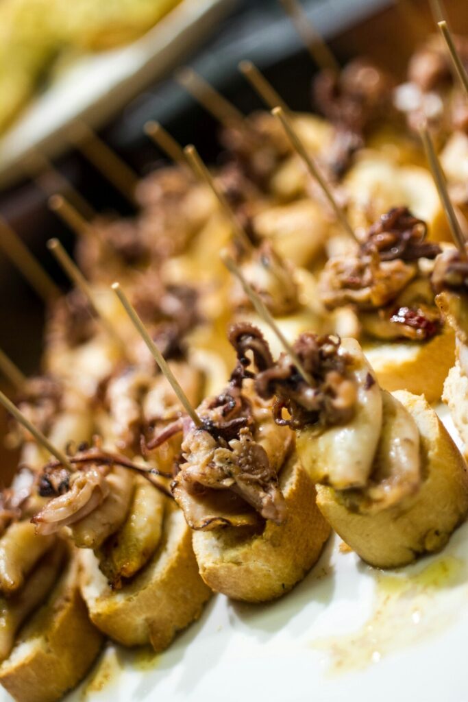 Pinchos de calamares sobre pan, presentados en una bandeja, listos para servir.